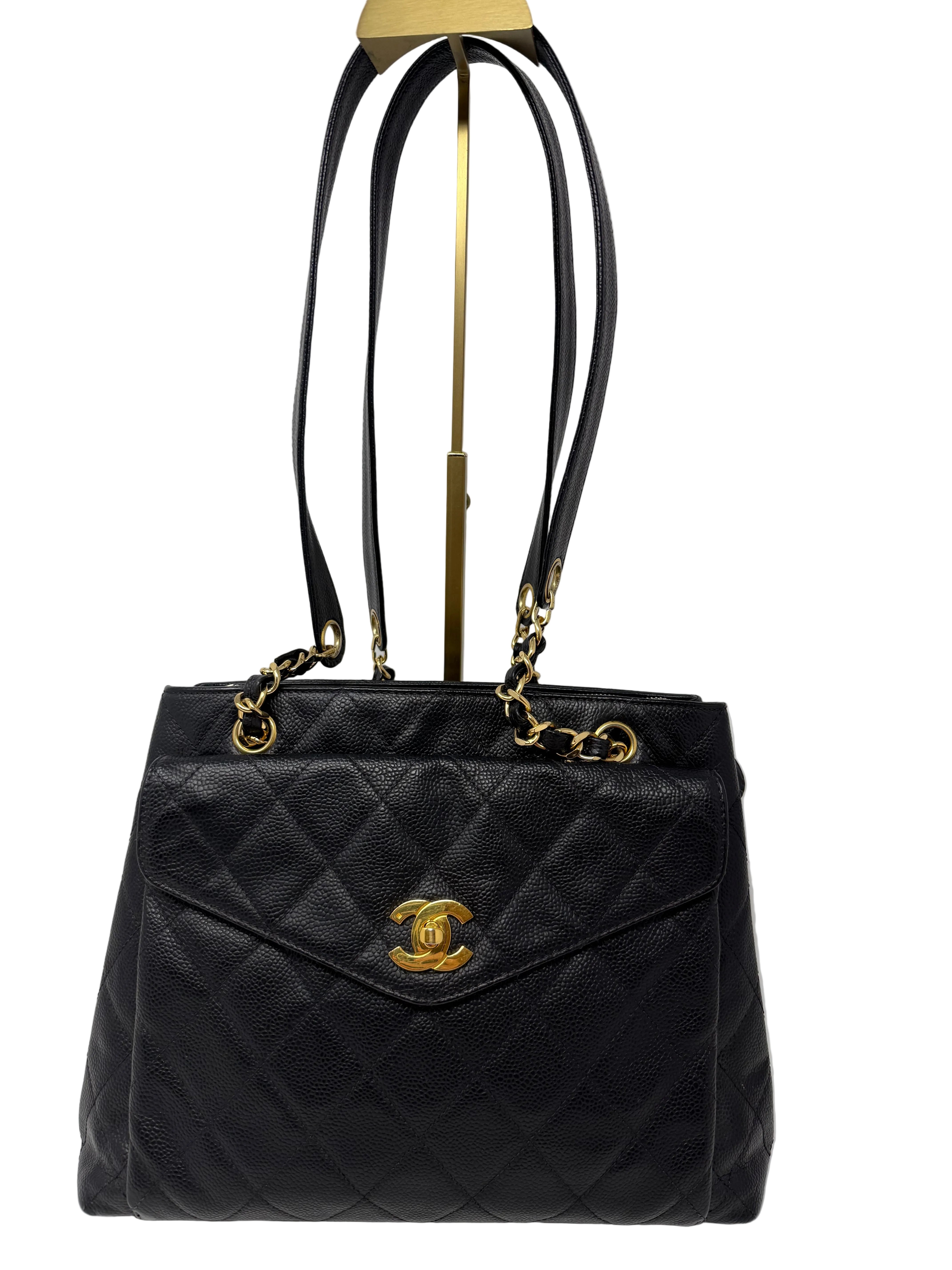 Black Chanel quilted handbag tote with gold hardware on a white background